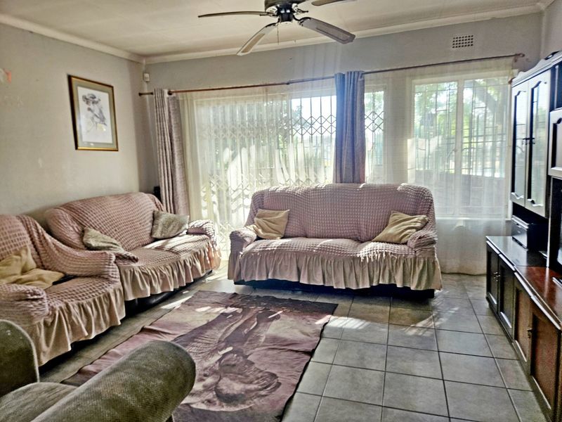 A living room featuring tiled flooring, a ceiling fan, and a sliding door with a security gate, providing access to the exterior.