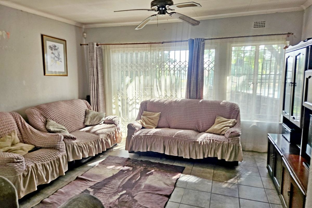 A living room featuring tiled flooring, a ceiling fan, and a sliding glass door with security gate leading to the exterior.