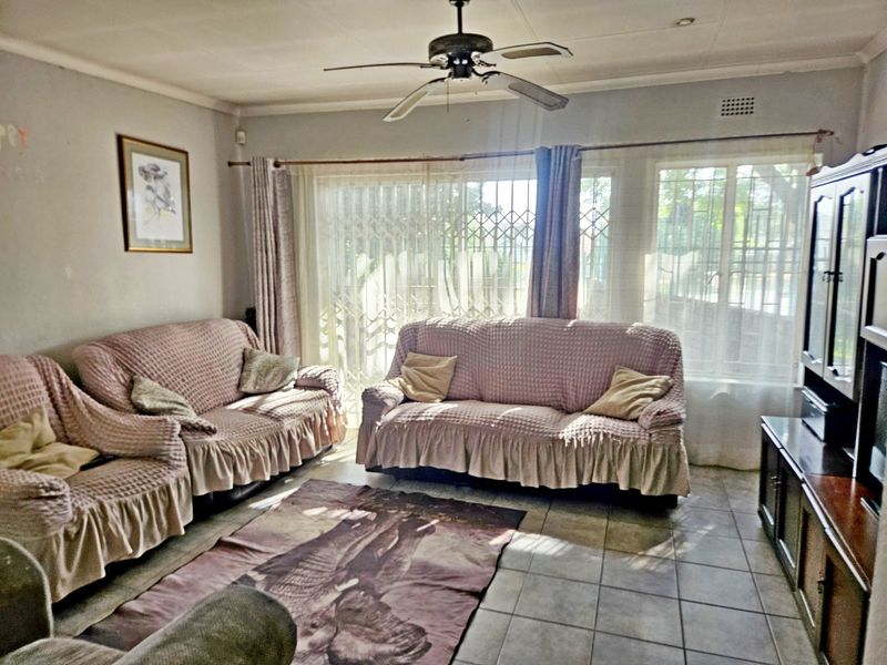 A living room featuring tiled flooring, a ceiling fan, and a sliding glass door with security gate leading to the exterior.