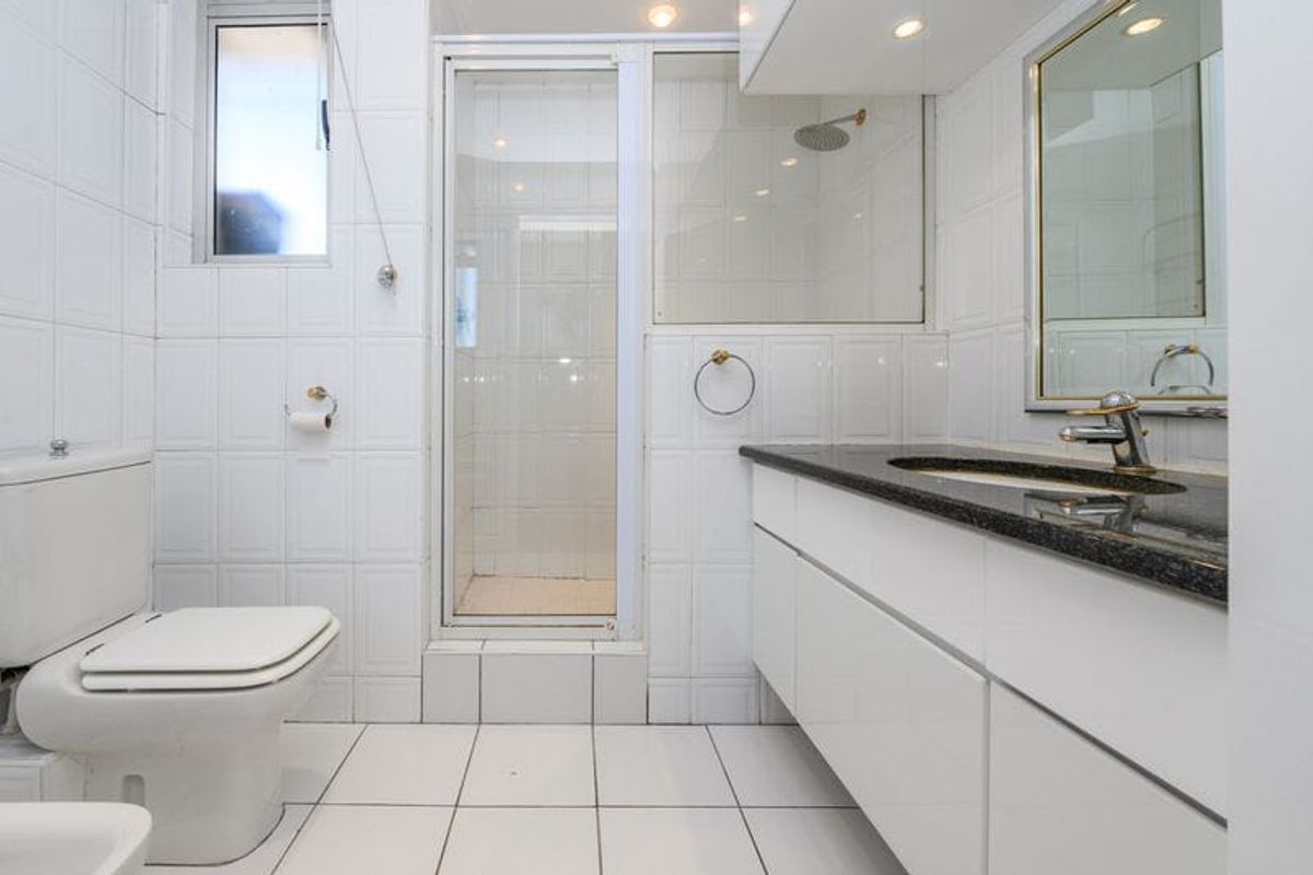 A clean, functional bathroom featuring a glass-enclosed shower, a vanity with a granite countertop, a wall-mounted toilet, and a bidet.