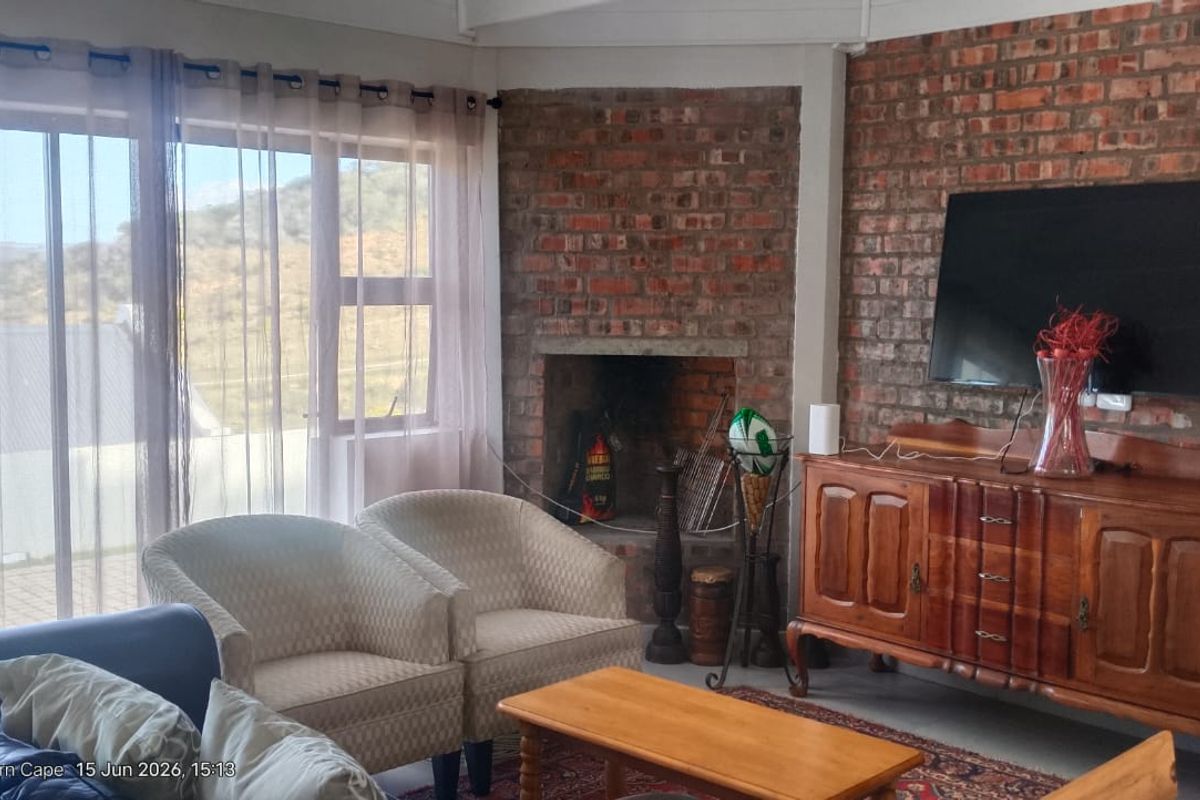 Living room featuring an exposed brick wall, a built-in fireplace, and large sliding glass doors providing natural light and scenic views.