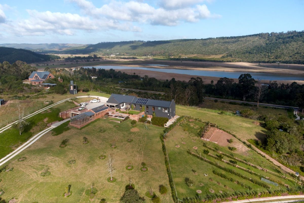 Aerial view of a modern farmhouse property featuring solar panels, extensive grounds, and scenic landscape views in a rural setting.