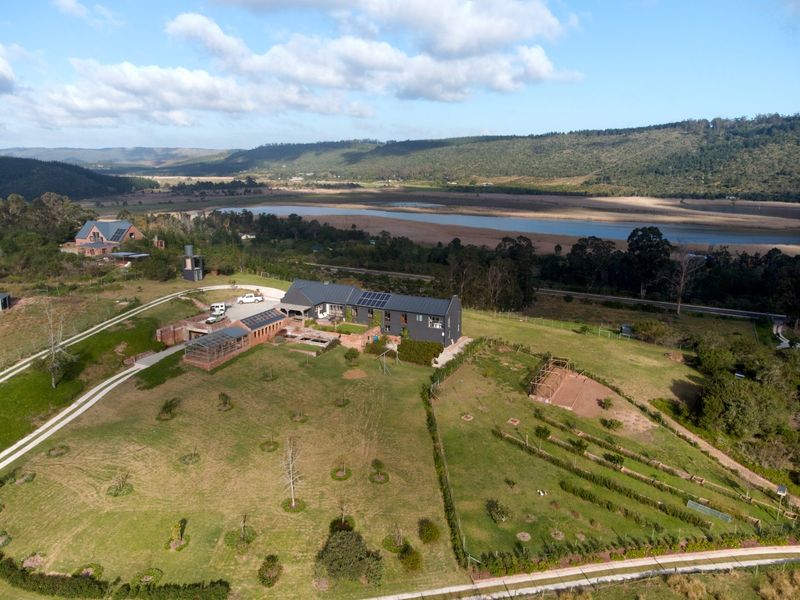 Aerial view of a modern farmhouse property featuring solar panels, extensive grounds, and scenic landscape views in a rural setting.