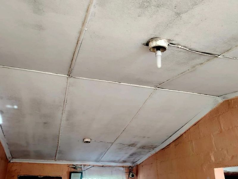Interior space featuring exposed ceiling panels with visible staining and exposed electrical wiring, requiring significant maintenance and cosmetic updates.