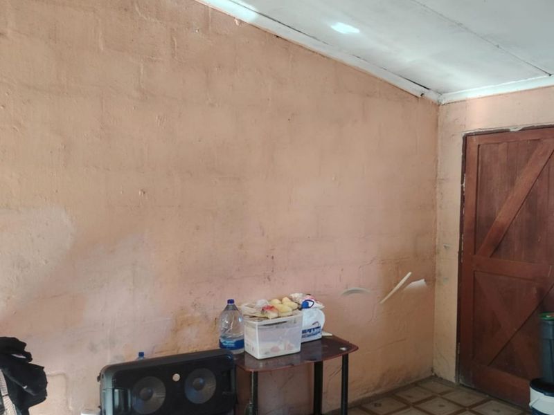 A utility space featuring tiled flooring and a timber door, currently showing significant wear to the wall and ceiling finishes.