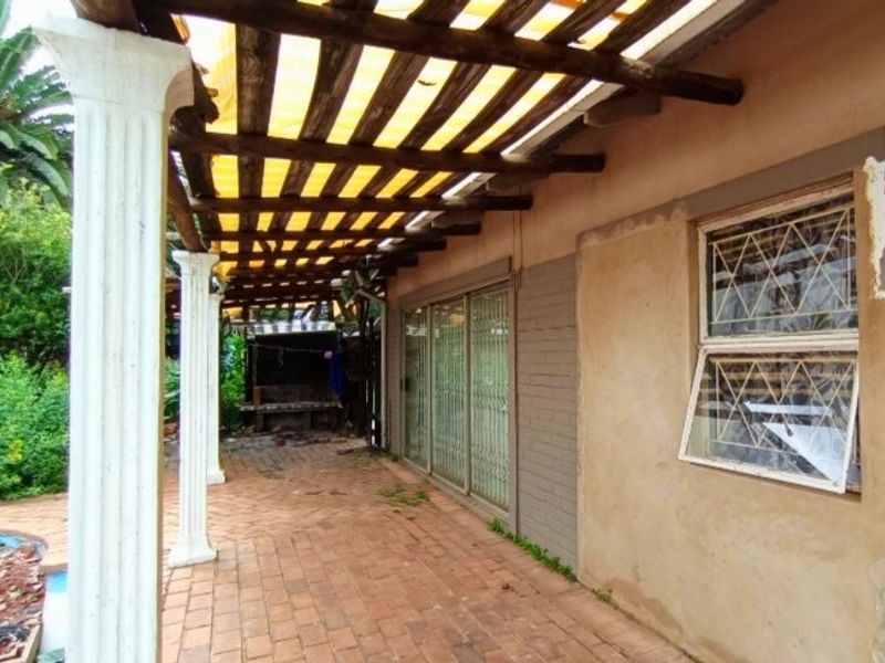 Covered patio area featuring brick paving, a timber pergola, and sliding door access to the main house interior.