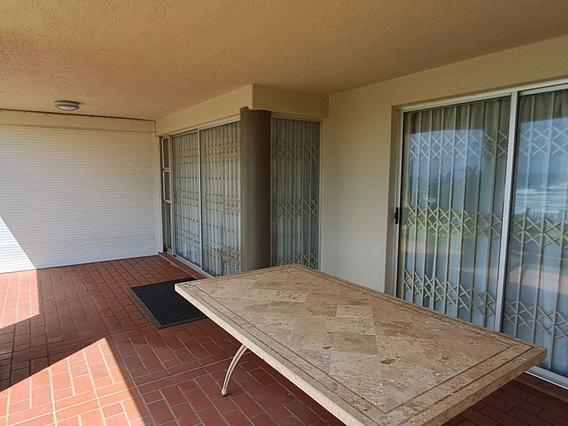 Covered patio area featuring terracotta tiled flooring, sliding glass doors with security gates, and a roller shutter for added privacy and security.