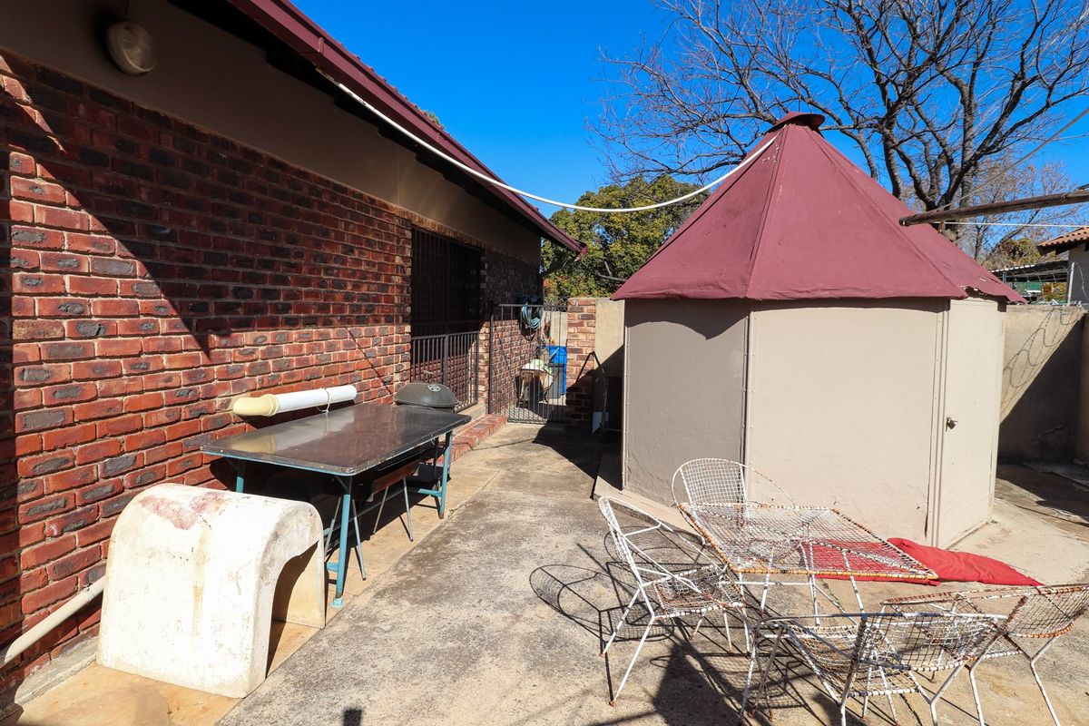 Rear exterior area featuring an exposed brick wall, concrete patio, and a lapa structure in the backyard.