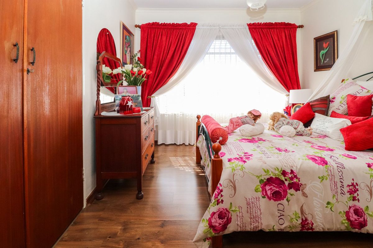 A cozy bedroom featuring laminate flooring and a built-in wardrobe, offering a functional space with natural light from the window.