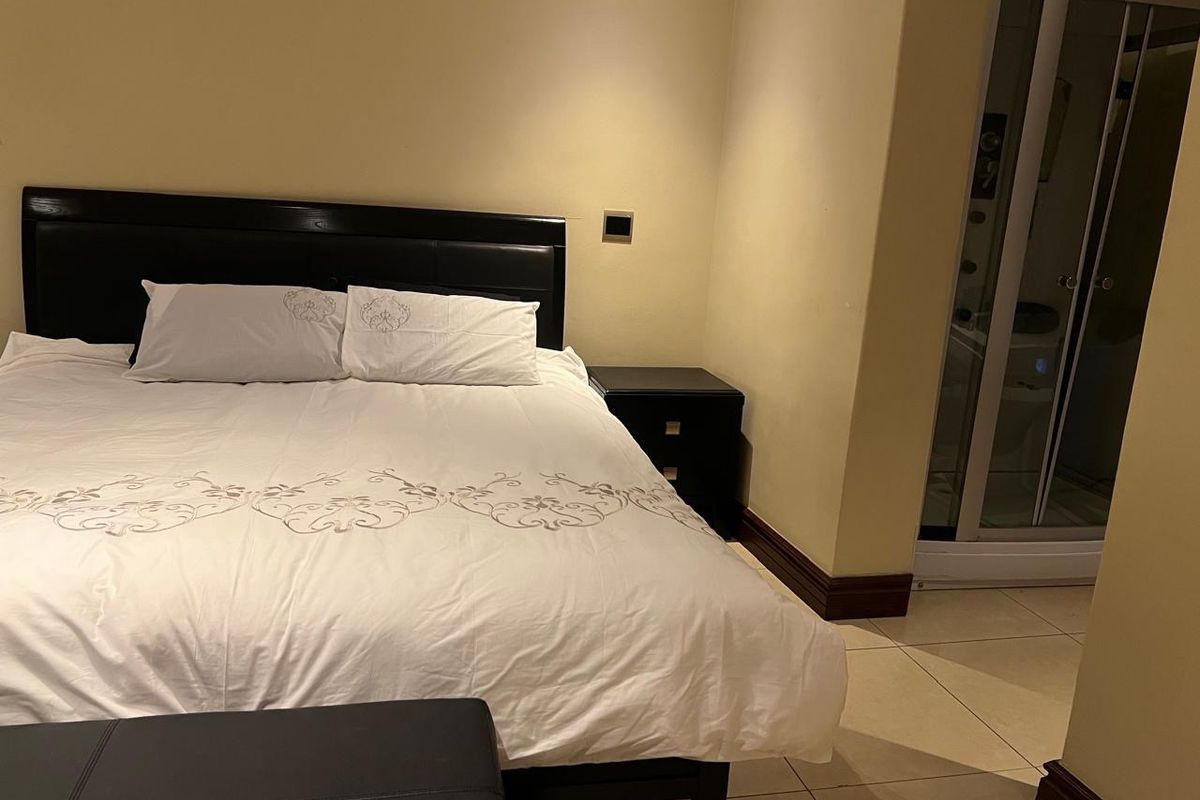 A bedroom featuring tiled flooring and an integrated en-suite shower cubicle.