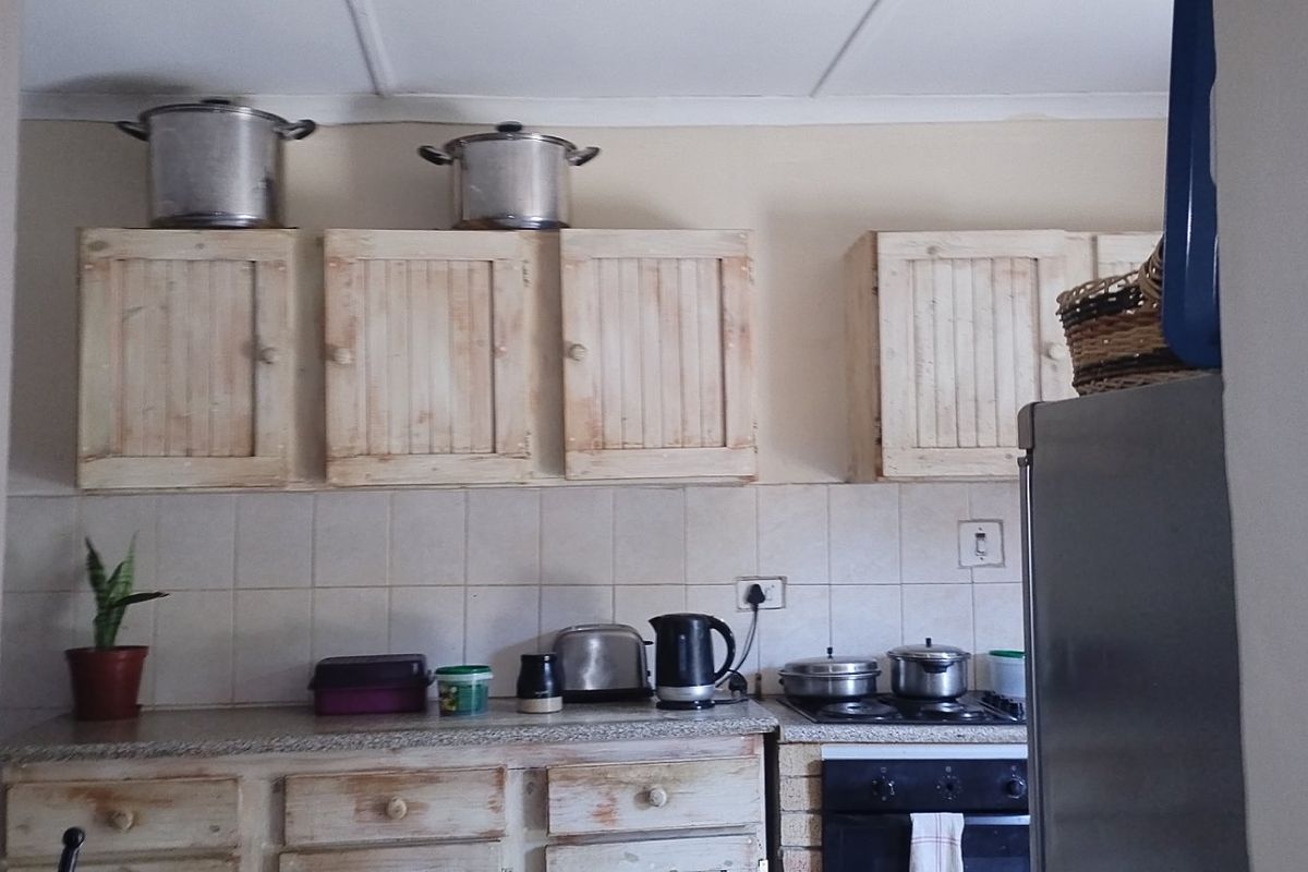 A functional kitchen featuring wooden cabinetry, tiled backsplash, and built-in cooking appliances, offering potential for a modern cosmetic update.