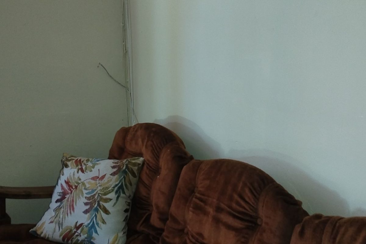 A corner view of a living area showing plain walls with visible exposed electrical wiring running along the corner.