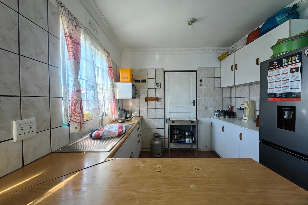 A functional kitchen featuring built-in cabinetry, laminate countertops, and a tiled backsplash, offering a practical layout with potential for modern updates.
