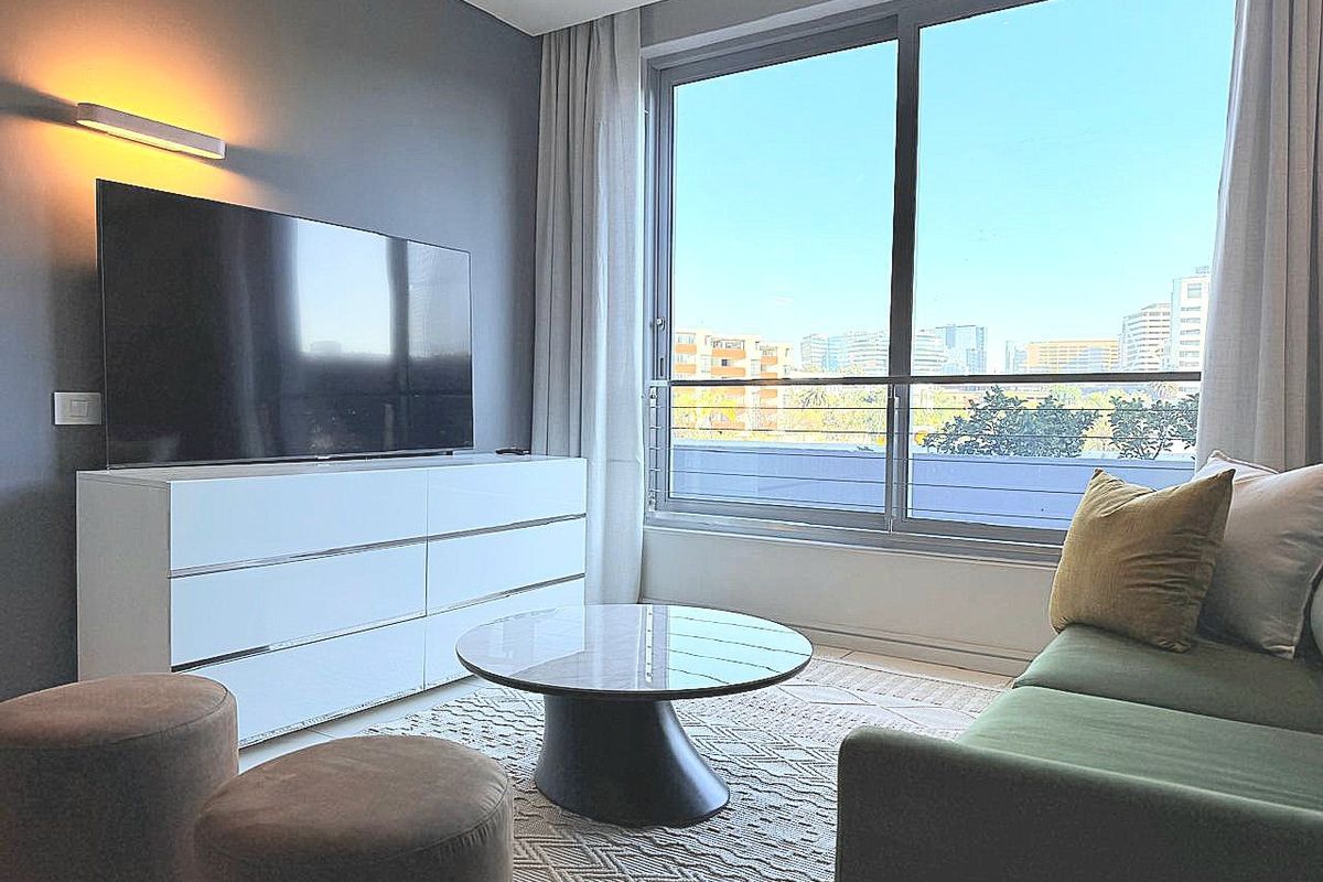 A modern living room featuring a large sliding glass door that provides ample natural light and views of the surrounding urban landscape.