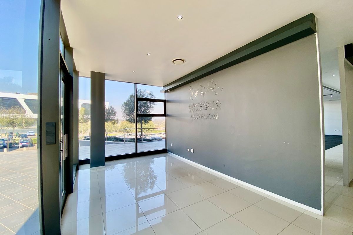 A bright and modern commercial entrance lobby featuring large floor-to-ceiling windows, polished tiled flooring, and a clean, professional aesthetic.