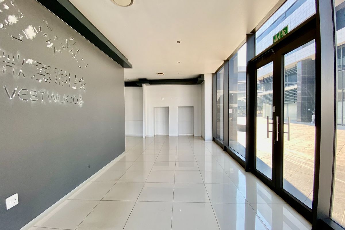 Modern commercial entrance lobby featuring polished tiled flooring, floor-to-ceiling glass windows, and recessed lighting, providing a bright and professional reception area.