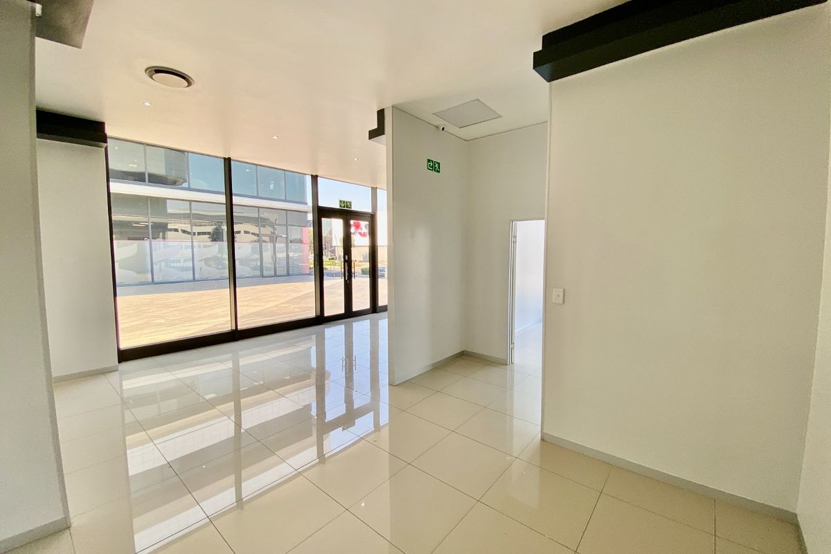 A bright, modern commercial entrance area featuring large glass windows, polished tiled flooring, and clean white walls, providing a professional and welcoming space.