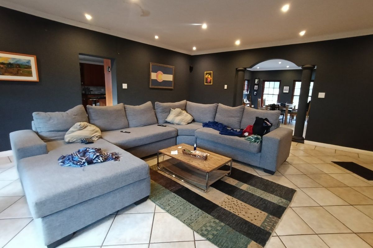 Spacious living room featuring dark painted walls, ceramic tiled flooring, recessed lighting, and an arched entryway leading to adjacent living spaces.
