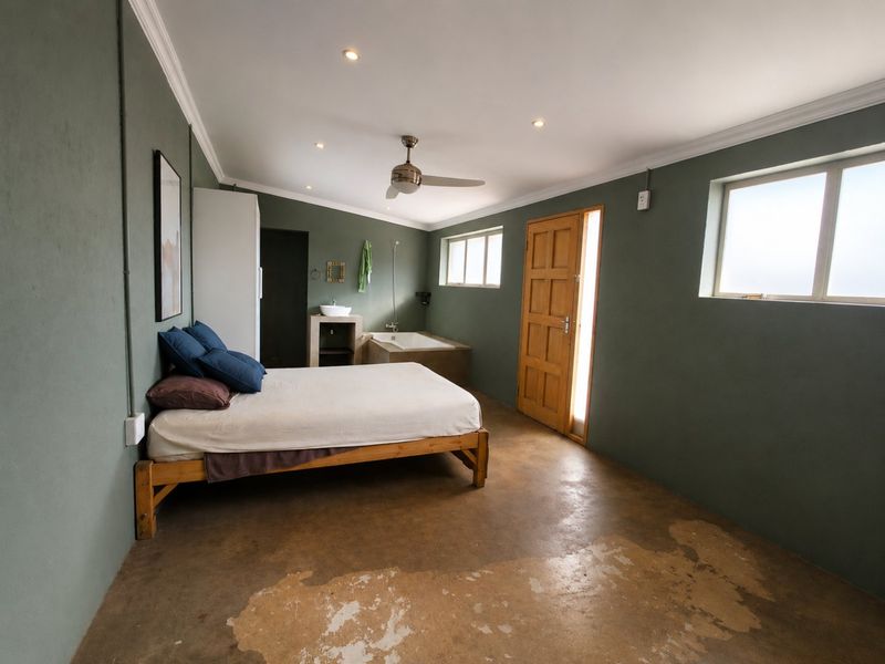 Spacious bedroom featuring an open-plan en-suite bathroom with a built-in bathtub, vessel sink, and polished concrete flooring.