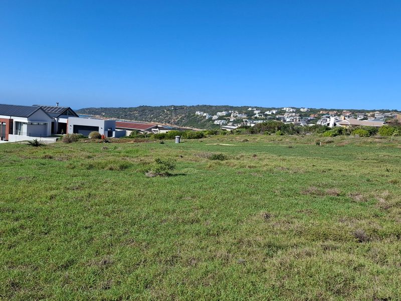 A scenic view overlooking a vacant residential plot with coastal and ocean vistas in the background.