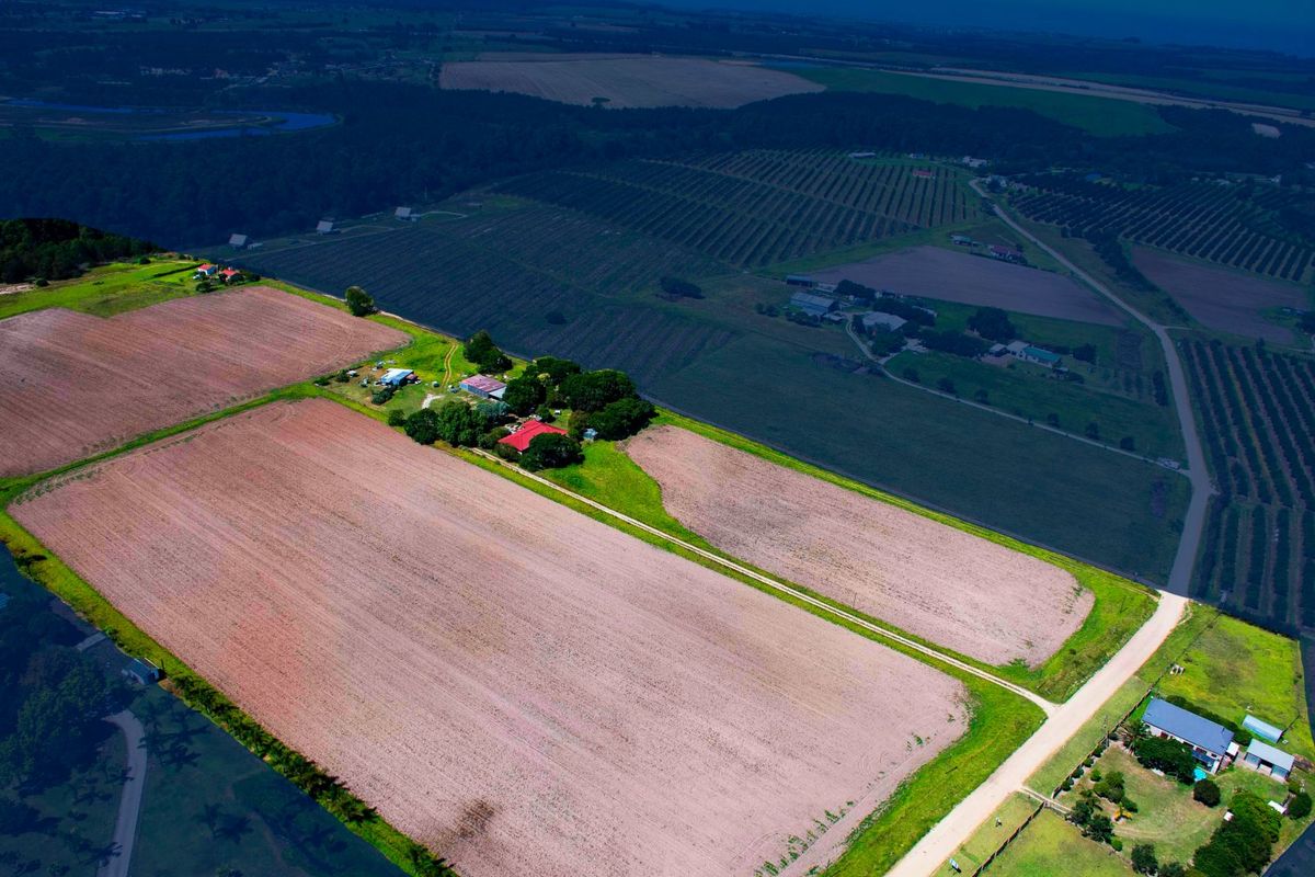 An aerial view of a large farm property featuring expansive cultivated fields, access roads, and the main farmhouse complex.