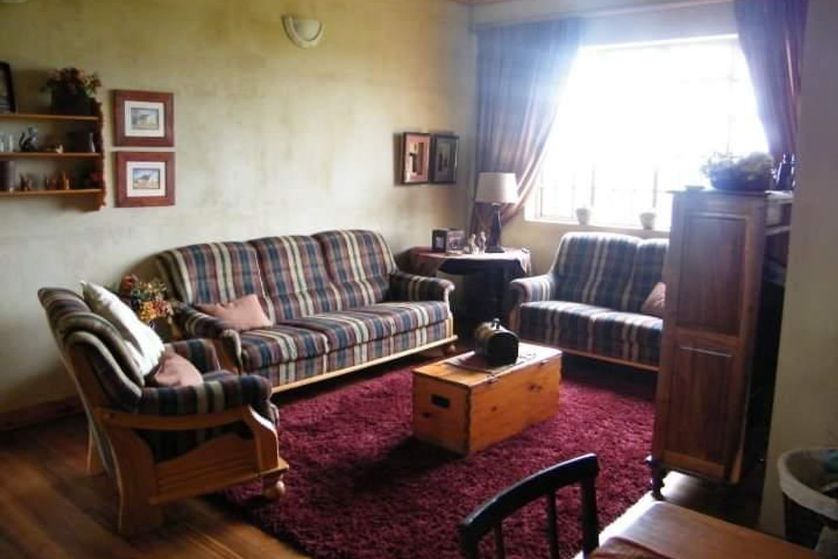A cozy living room featuring warm-toned textured walls, hardwood flooring, and classic coved ceiling detailing, providing a comfortable and traditional living space.