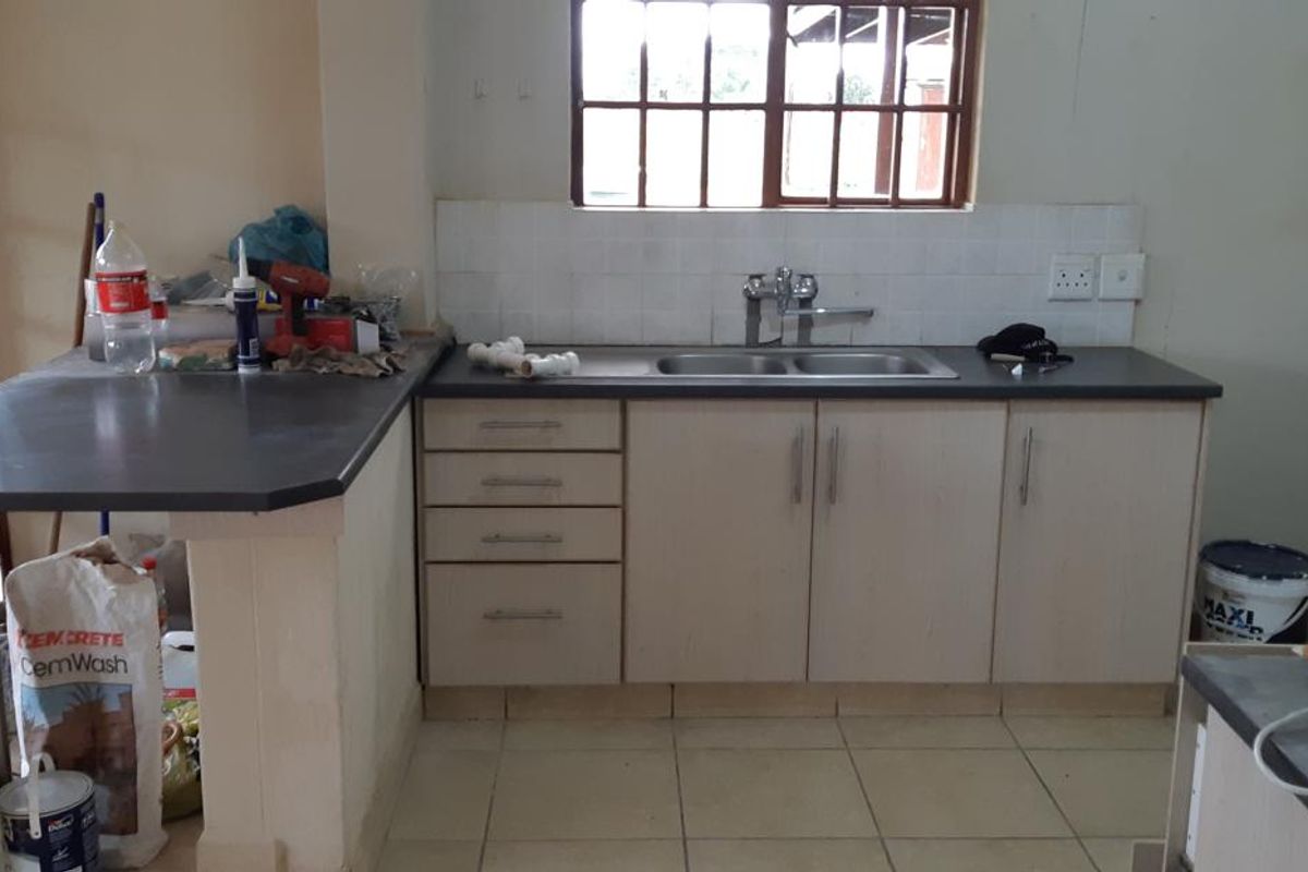 A functional kitchen area featuring laminate cabinetry, a double bowl sink, tiled splashback, and tiled flooring.