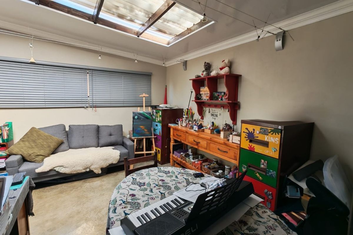A multi-purpose living space featuring a large skylight, concrete flooring, and venetian blinds, offering a bright and functional area for various activities.