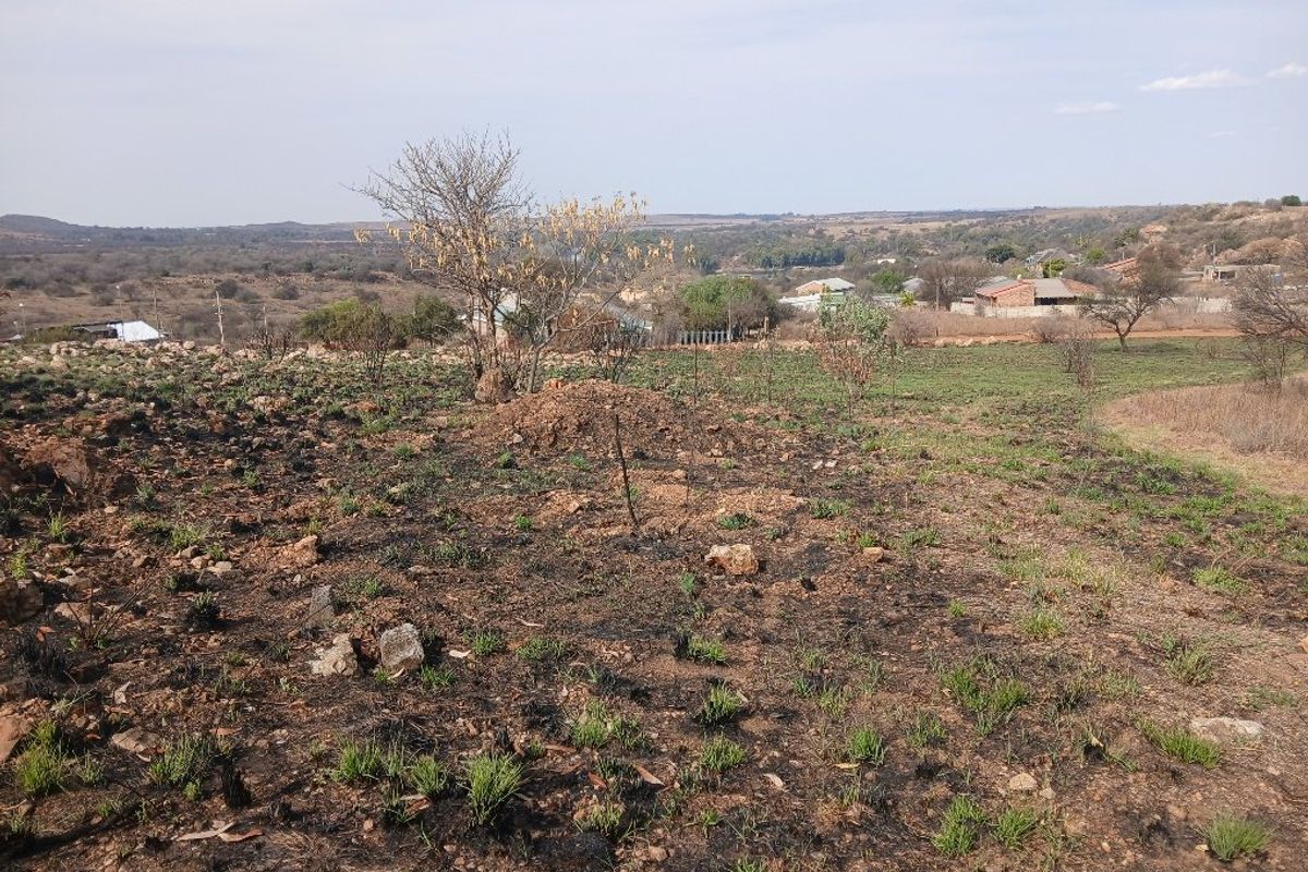 A wide-angle view of the vacant residential land, showing natural terrain and surrounding landscape with signs of recent vegetation clearing or fire damage.