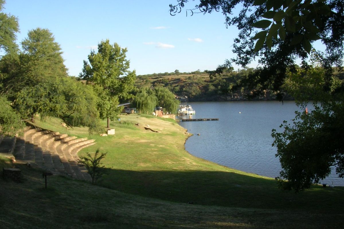 A scenic view of the waterfront property featuring natural landscaping, mature trees, and stone terraced seating leading down to the water's edge.