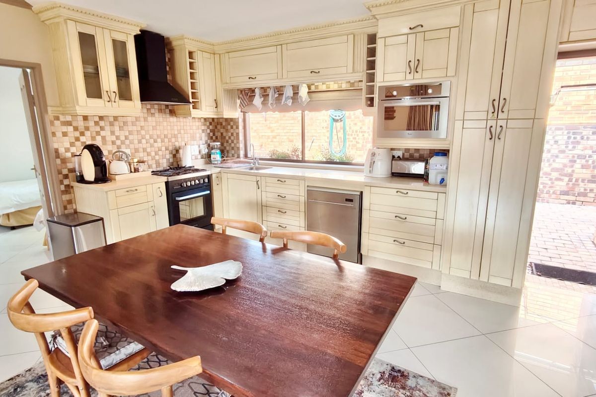 A functional kitchen featuring cream-toned cabinetry, built-in appliances, a tiled backsplash, and direct access to an outdoor area.