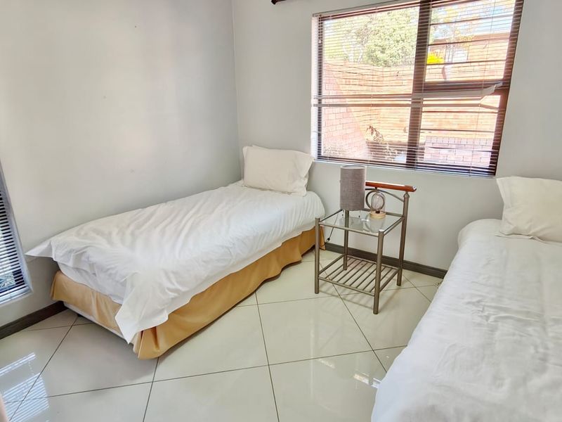 A bedroom featuring tiled flooring and venetian blinds, providing a functional space with natural light.