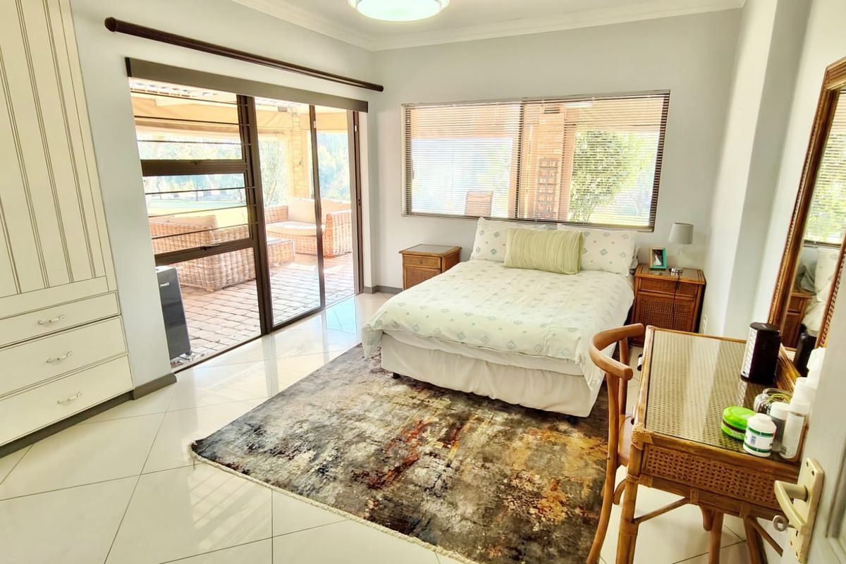 Spacious bedroom featuring built-in wardrobes, tiled flooring, and large sliding glass doors providing direct access to an outdoor patio area.