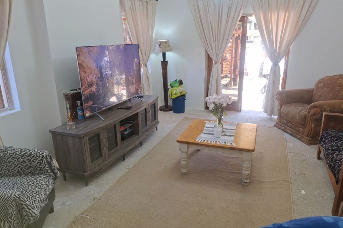 A living room featuring french doors leading to an outdoor area and unfinished concrete flooring, offering potential for renovation and flooring upgrades.