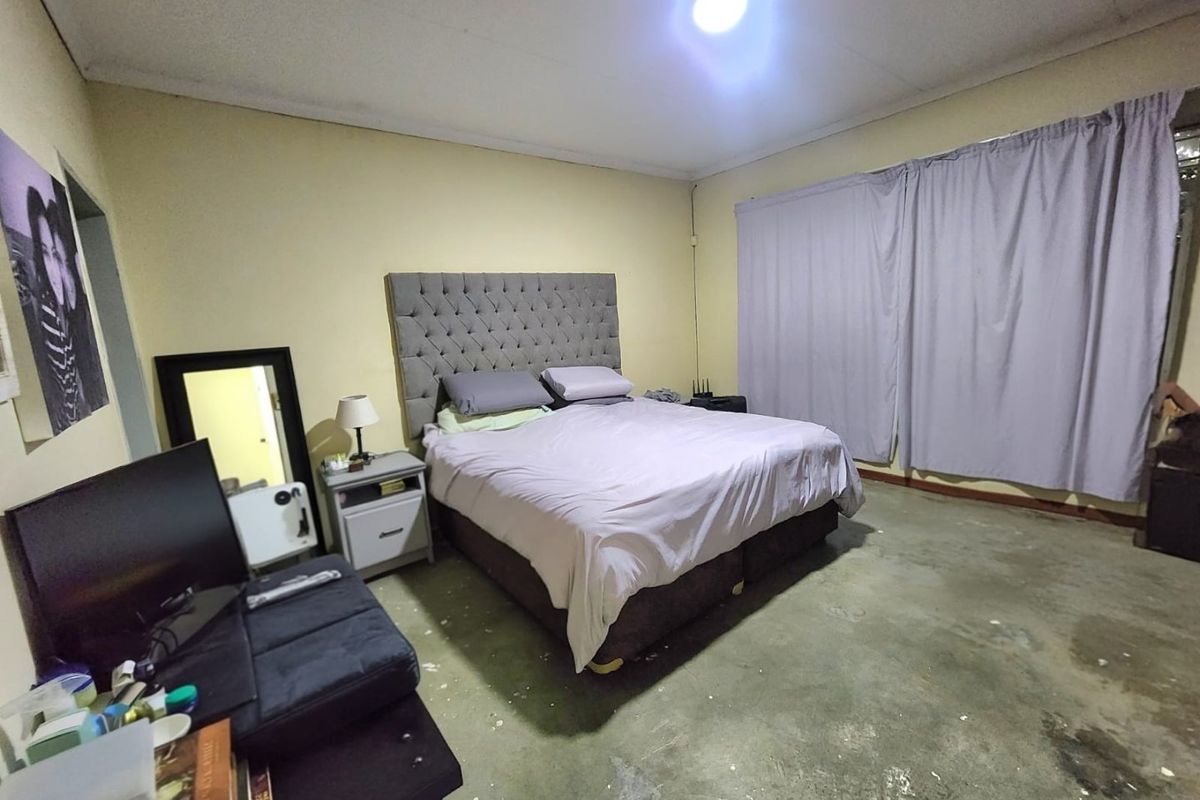 A bedroom featuring exposed concrete flooring and neutral wall tones, offering a blank canvas for potential renovation and interior design updates.
