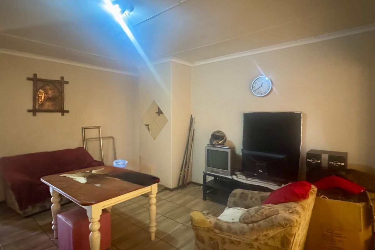 A living room area featuring ceramic floor tiles and coved ceiling cornices, currently requiring cosmetic updates to improve the overall aesthetic and finish.