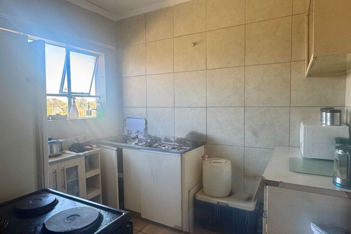 A dated kitchen featuring tiled splashbacks, built-in cabinetry, and a sink, requiring significant renovation and modernization to improve functionality and aesthetic appeal.