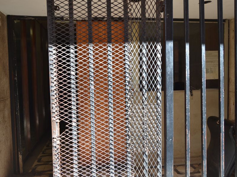 Entrance area featuring a heavy-duty metal security gate and bars, showing significant signs of wear and corrosion.