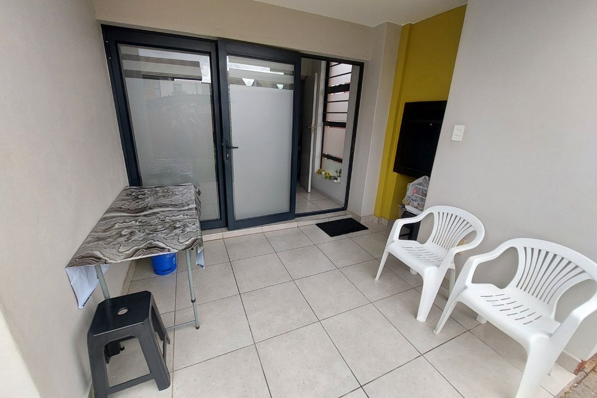 A covered patio area featuring tiled flooring and modern aluminium sliding doors, providing a functional outdoor space for relaxation.