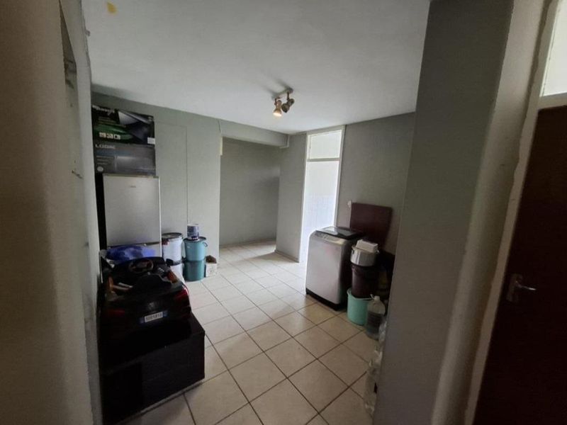A functional laundry area featuring tiled flooring and direct access to an adjacent space, providing a practical utility zone for the apartment.