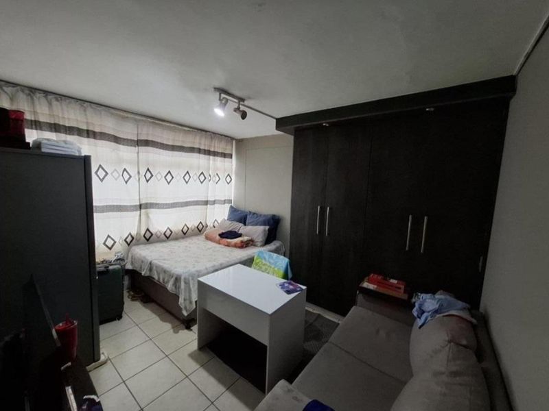 A functional bedroom featuring built-in dark wood cupboards and tiled flooring, providing practical storage and living space.