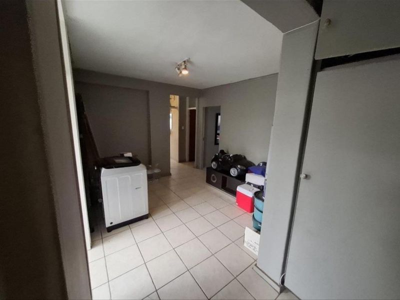 A functional laundry area featuring tiled flooring and built-in storage cabinetry, providing practical utility space within the apartment.