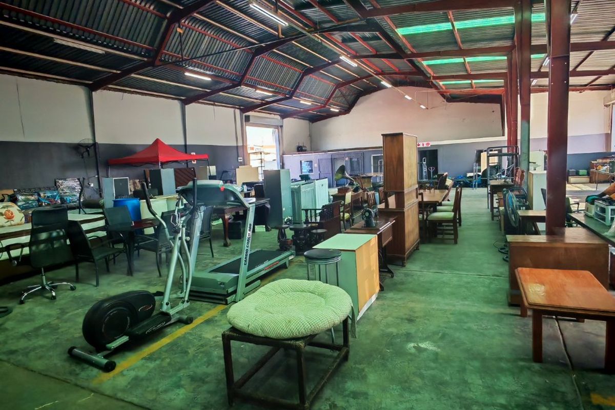 Spacious industrial warehouse unit featuring exposed steel roof trusses, translucent roof panels for natural light, and durable concrete flooring.