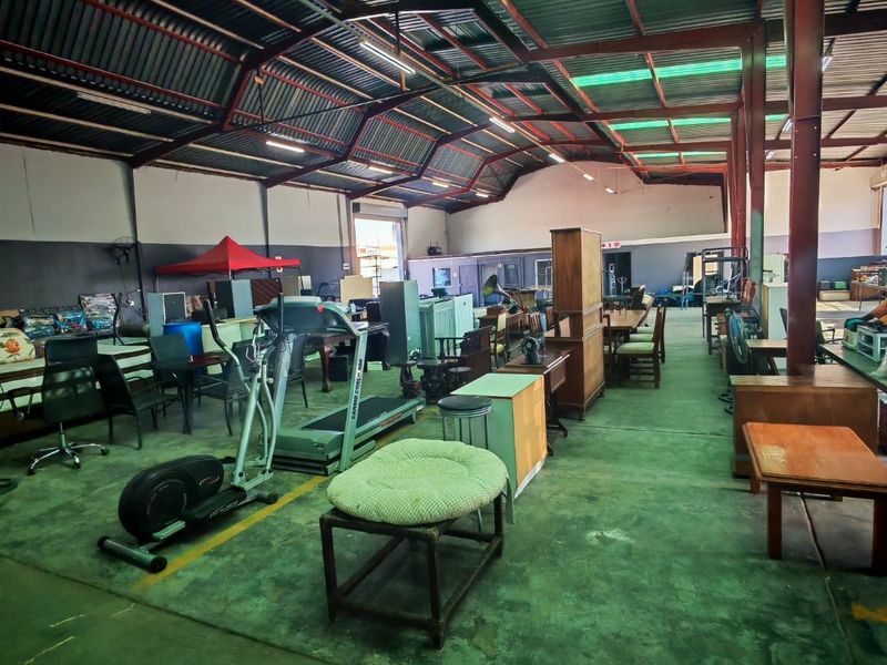 Spacious industrial warehouse unit featuring exposed steel roof trusses, translucent roof panels for natural light, and durable concrete flooring.