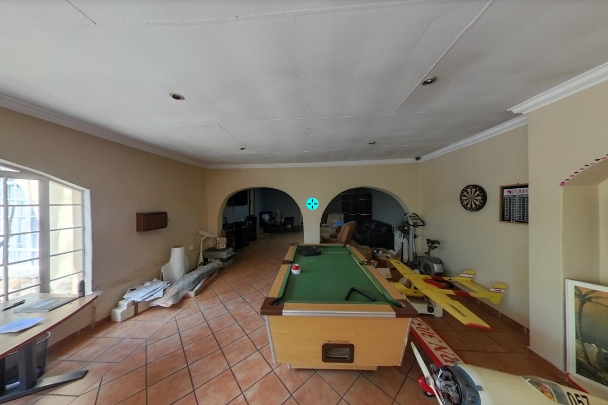 Spacious living area featuring tiled flooring, arched architectural details, and recessed lighting, currently utilized as a multi-purpose hobby room.