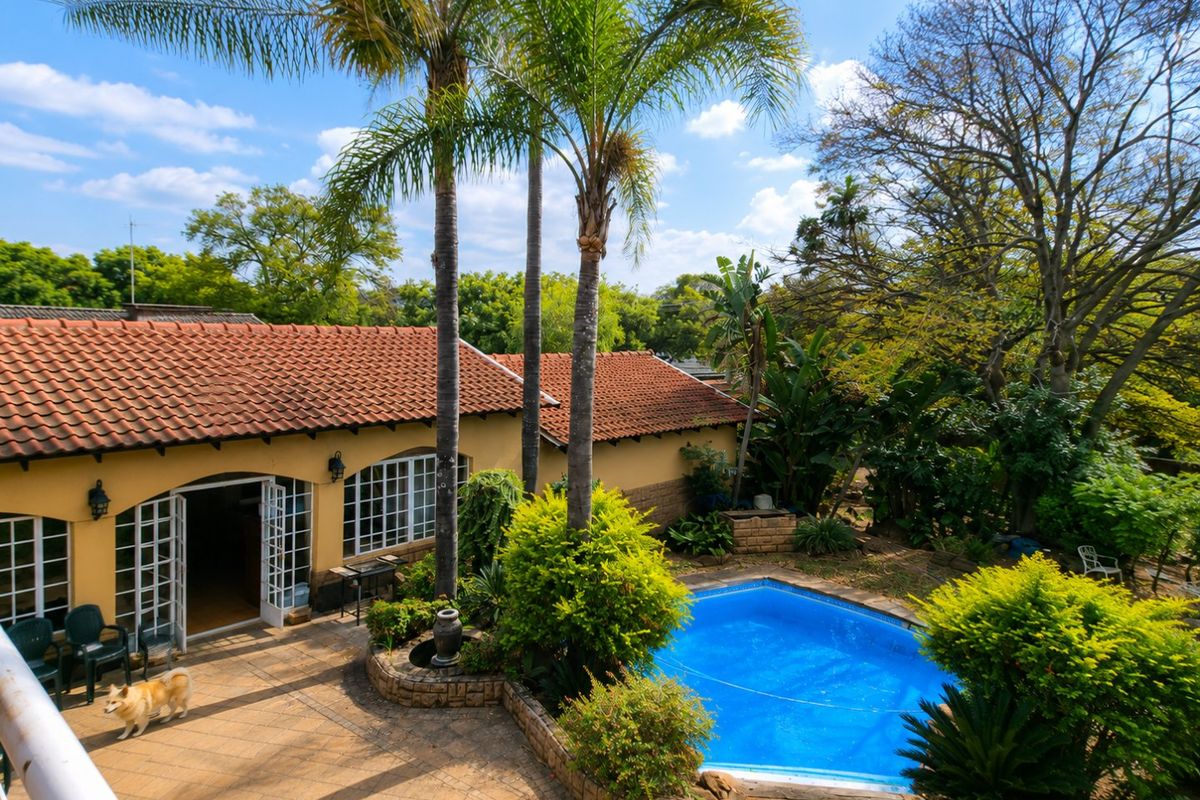 A spacious rear garden featuring a swimming pool, paved patio area, and established landscaping, providing a private outdoor entertainment space.