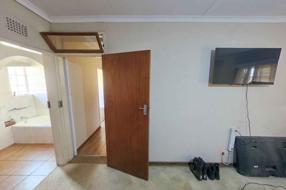 Bedroom featuring a timber door, transom window, and direct access to an adjoining bathroom with tiled flooring.