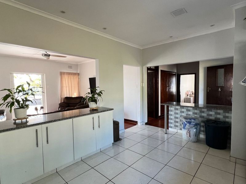 Open-plan kitchen and living area featuring tiled flooring, granite countertops, and a breakfast bar, creating a functional and connected living space.