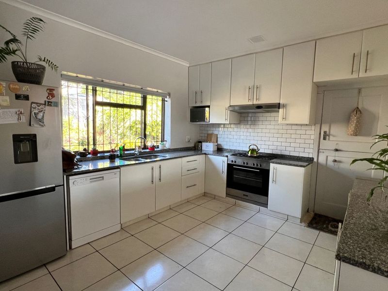A functional kitchen featuring white cabinetry, granite countertops, a subway tile backsplash, and integrated stainless steel appliances.
