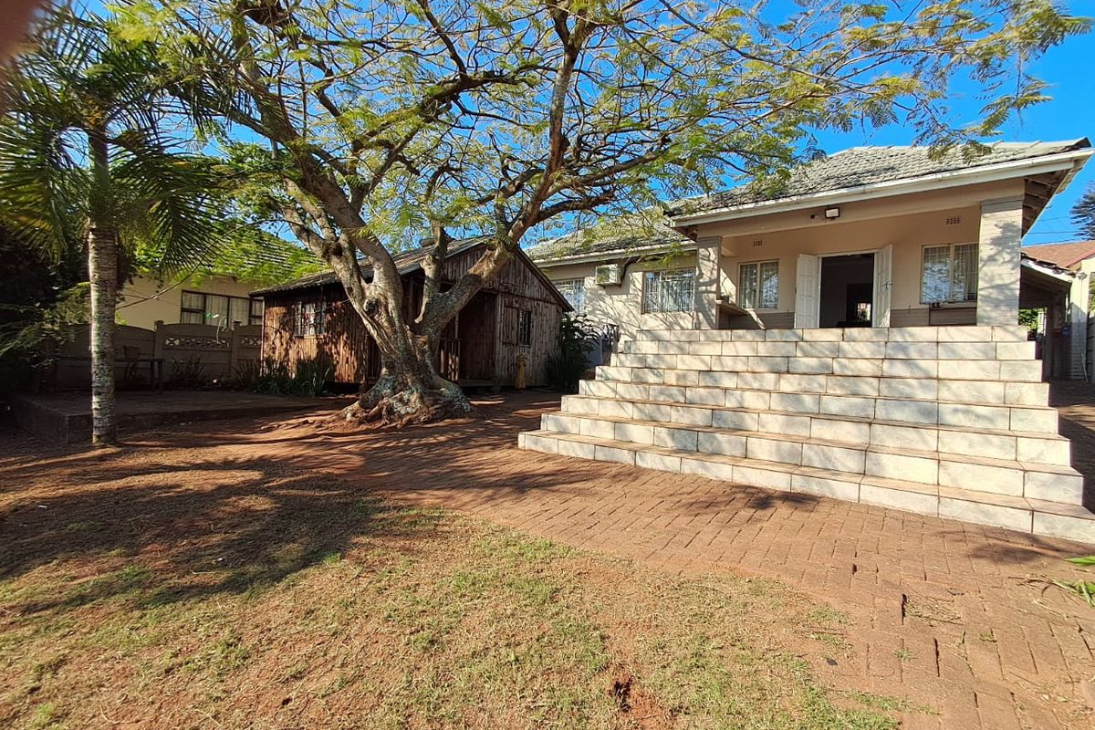 Rear view of the property featuring a large tiled staircase leading to the main house, a paved patio area, and a separate timber outbuilding.